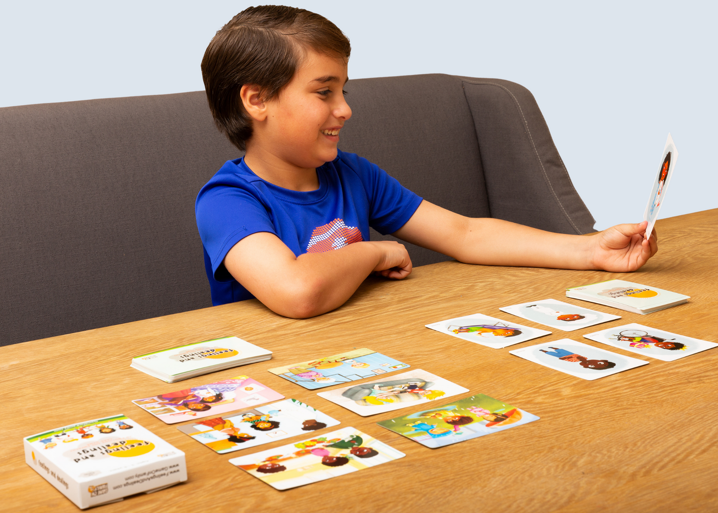 Child playing the Feelings and Dealings card game with colorful cards on a wooden table.
