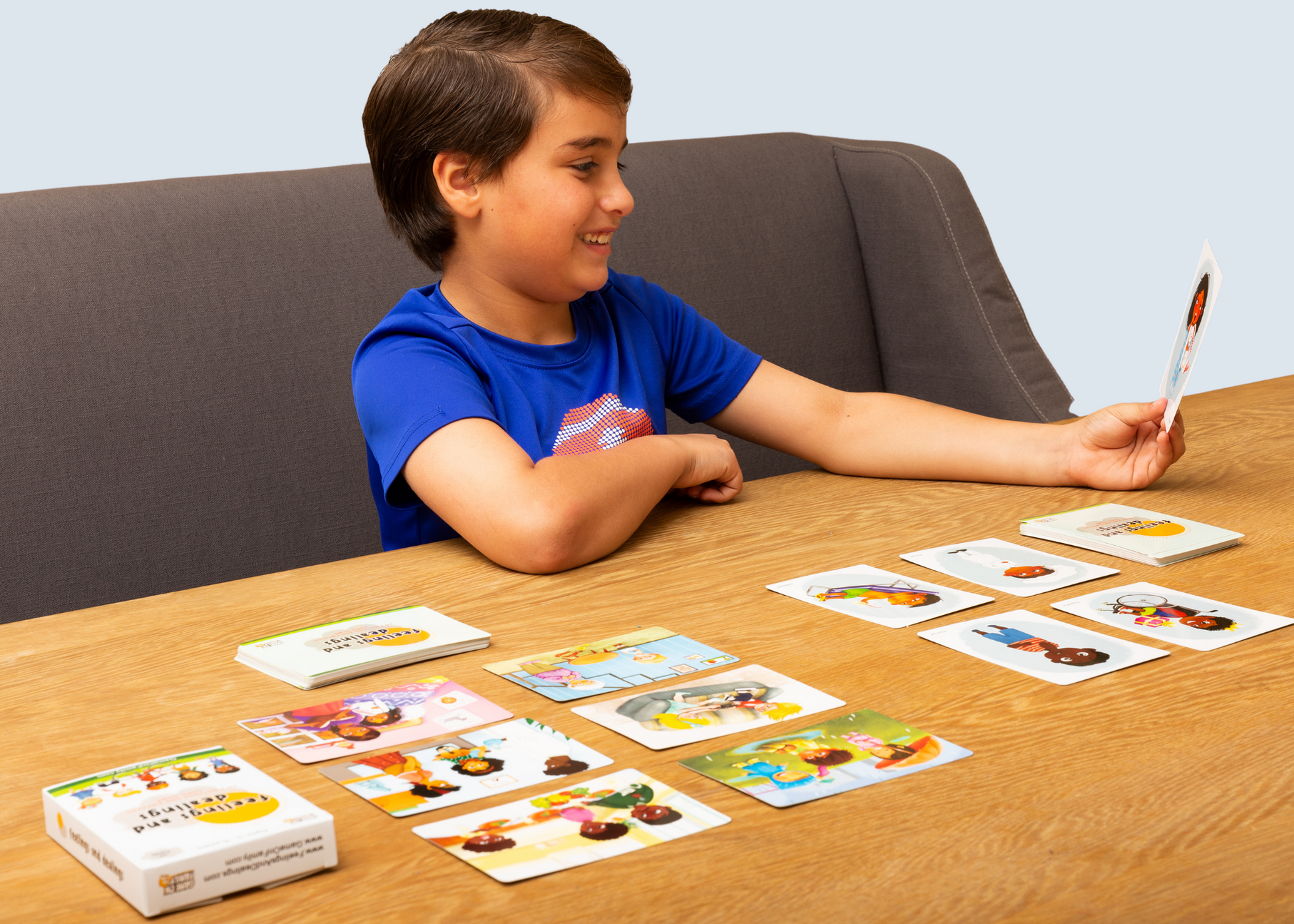 Child playing the Feelings and Dealings card game with colorful cards on a wooden table.